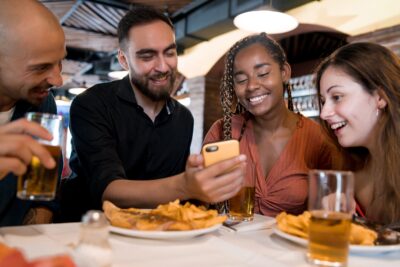 grupo comendo em restaurante olhando celular